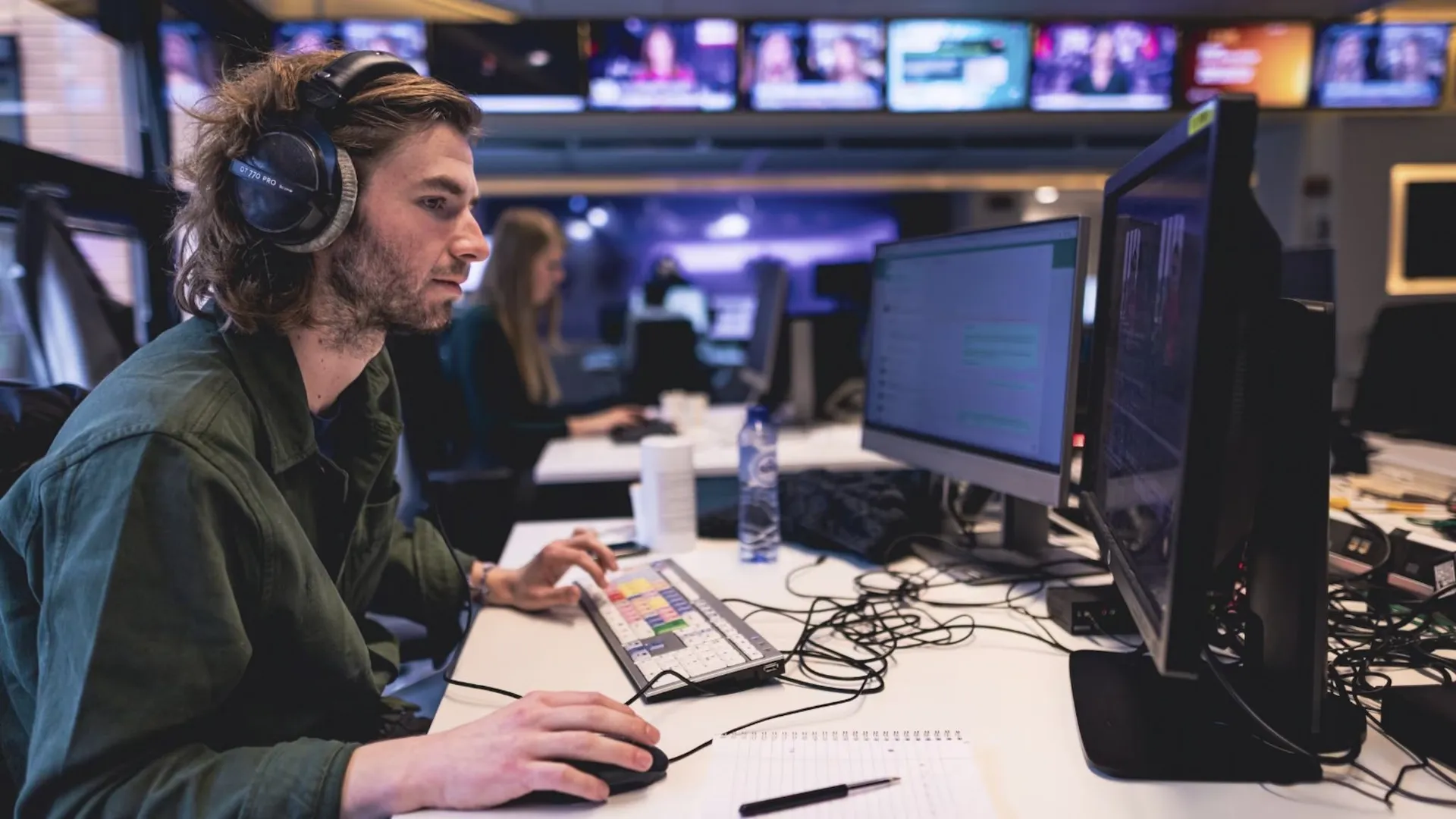 Redacteur met koptelefoon aan het werk op een nieuwsredactie
